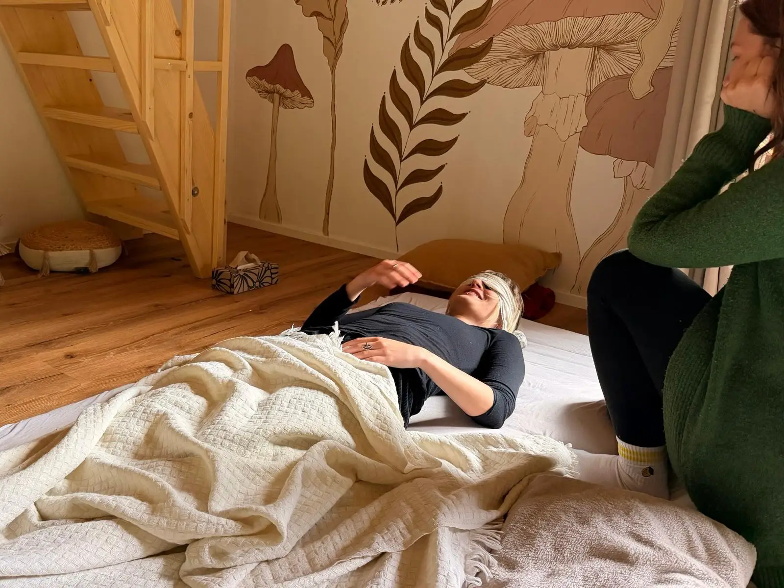 Účastnice leží na žíněnce s facilitátorkou vedle